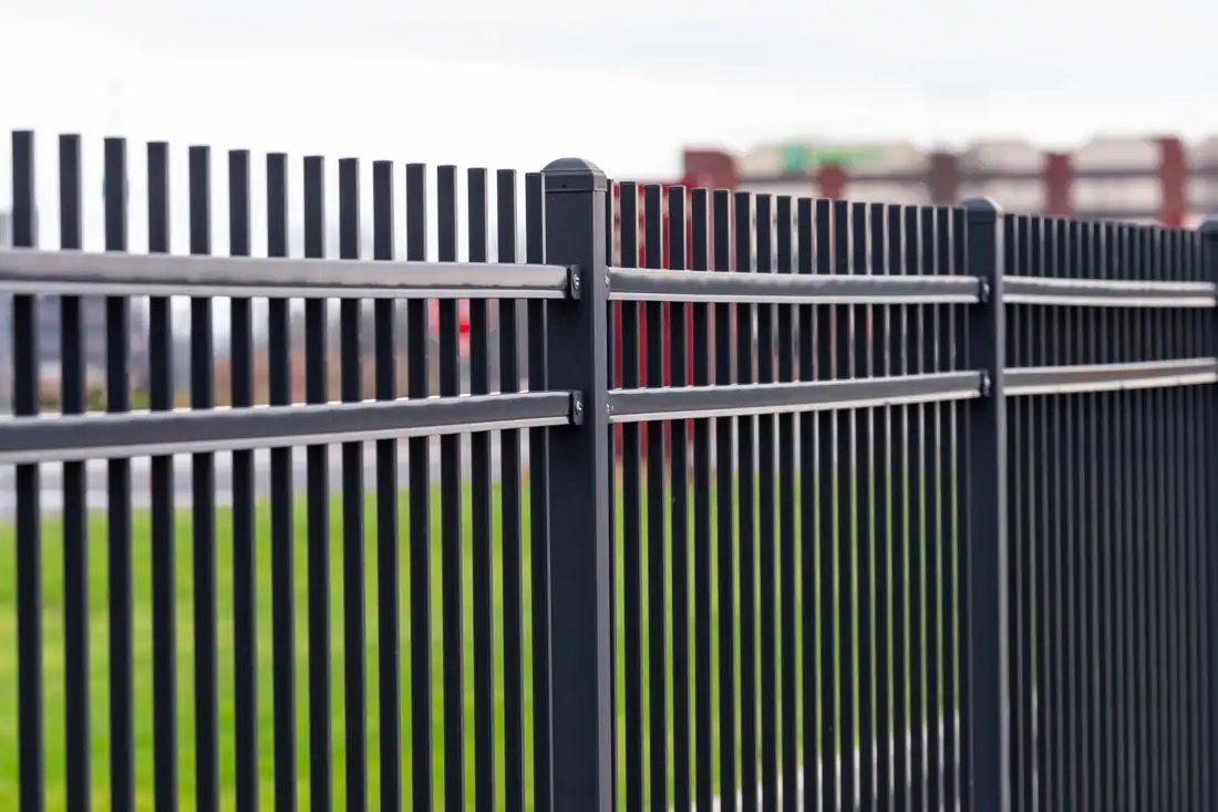 Close-up of black aluminum fence pickets and rails
