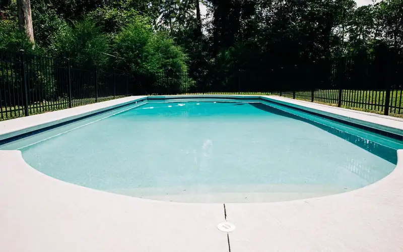 Black aluminum pool fence surrounding an in-ground swimming pool