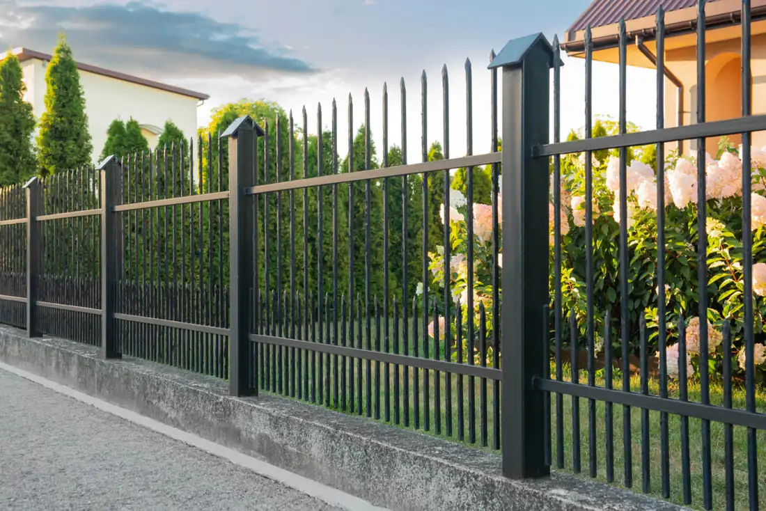 Black aluminum fence following a gentle slope in a landscaped yard