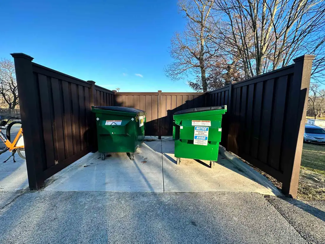 Black steel-framed dumpster enclosure with double gates