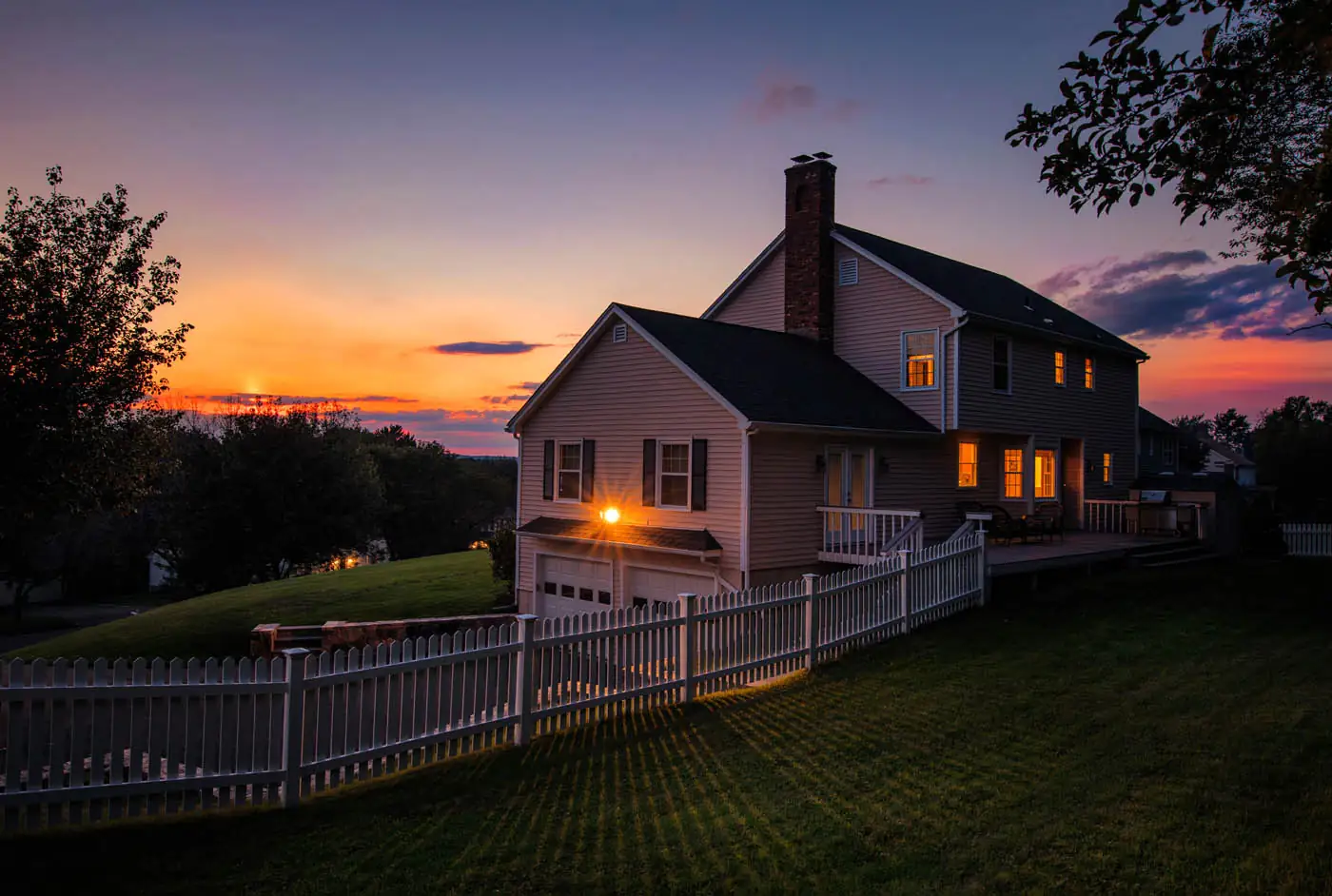 Colonial house at dusk with an aluminum fence along the front yard