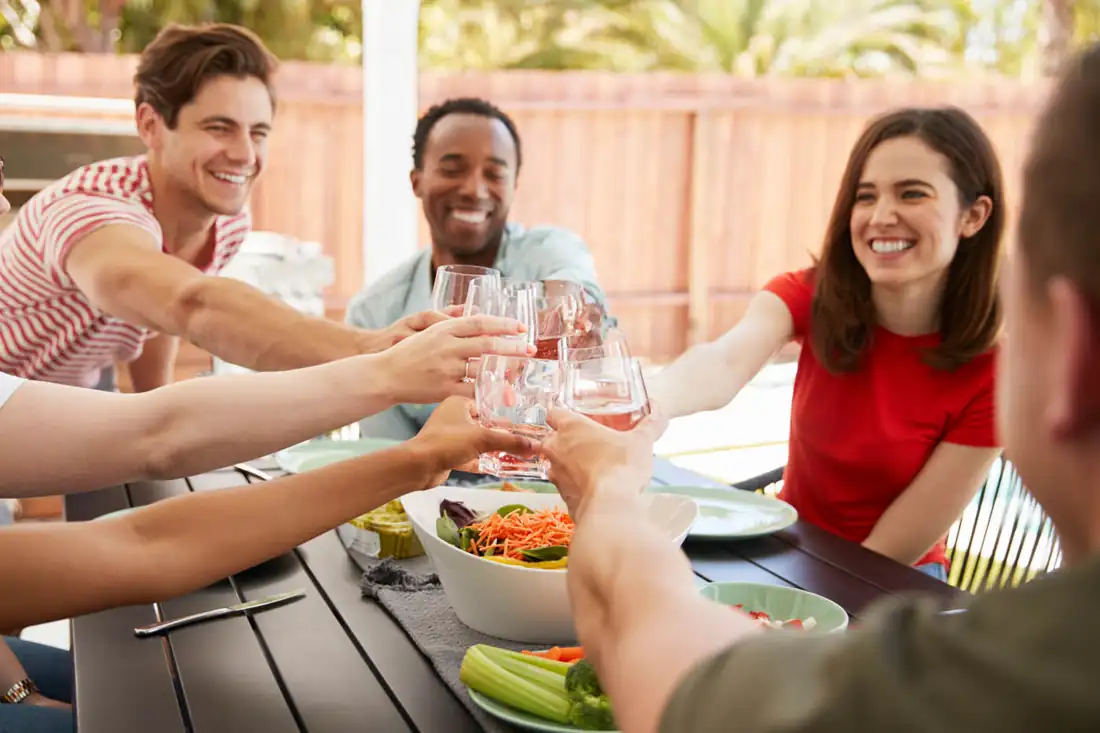 Family eating dinner on a backyard patio enclosed by a fence