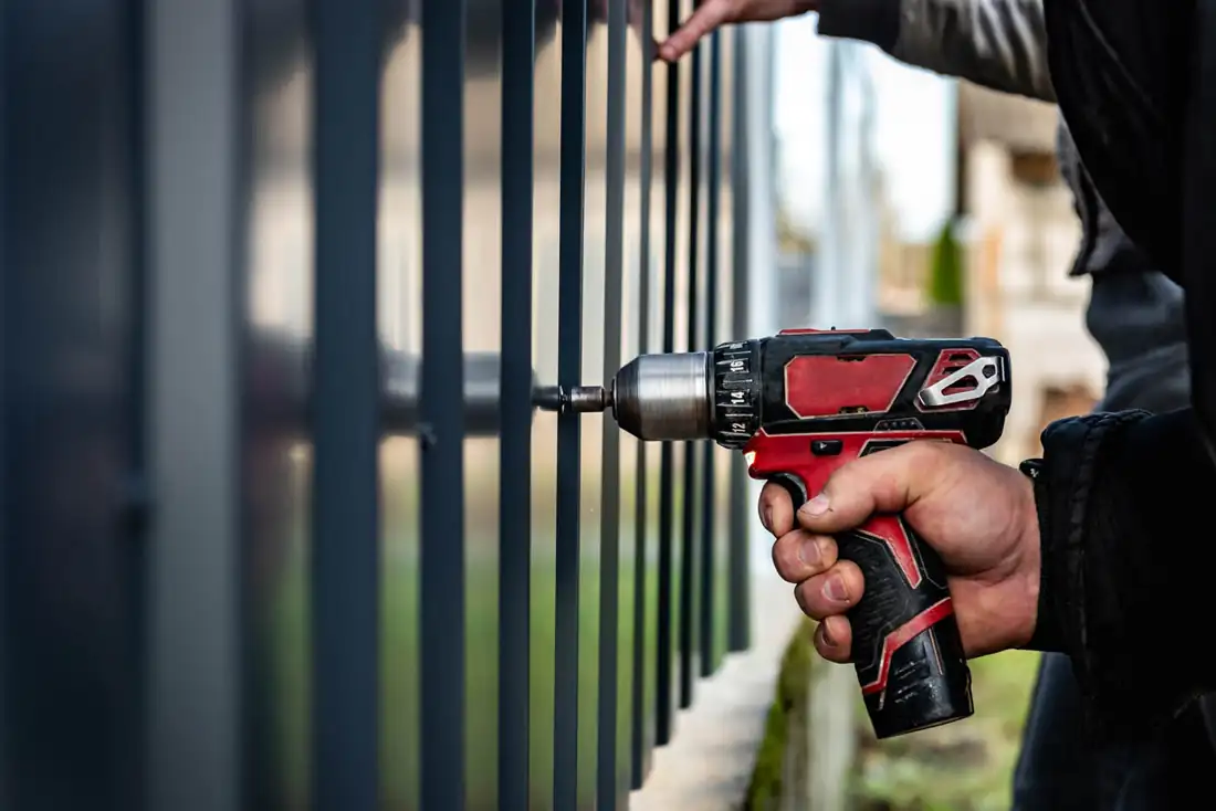 Installer using a power tool to assemble a fence section