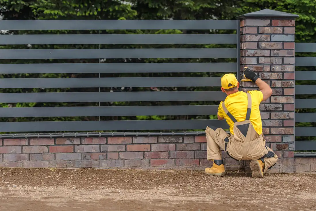 Crew installing horizontal fence boards next to a brick wall