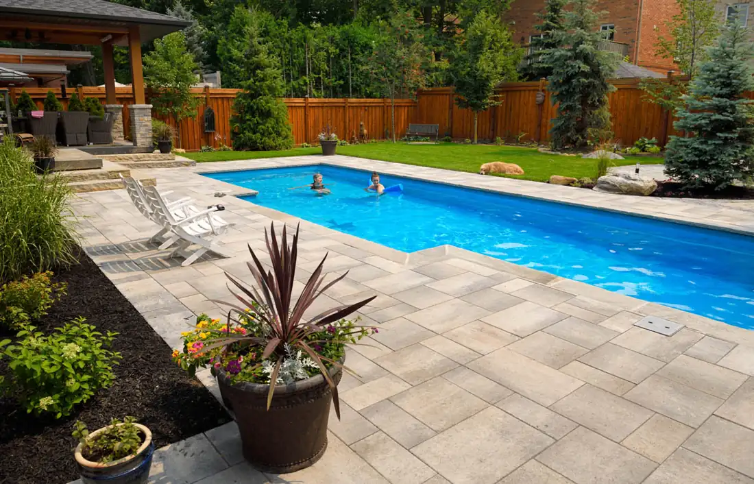 Family relaxing in a fenced backyard with a pool