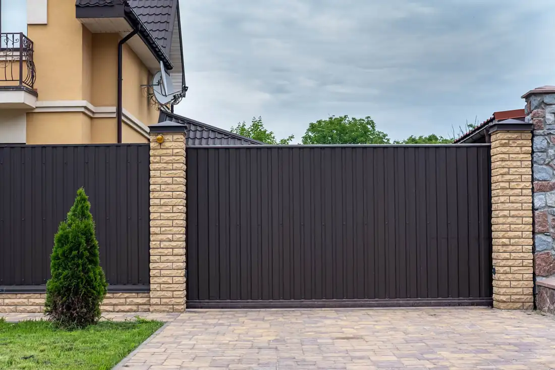 Steel driveway gate between brick pillars