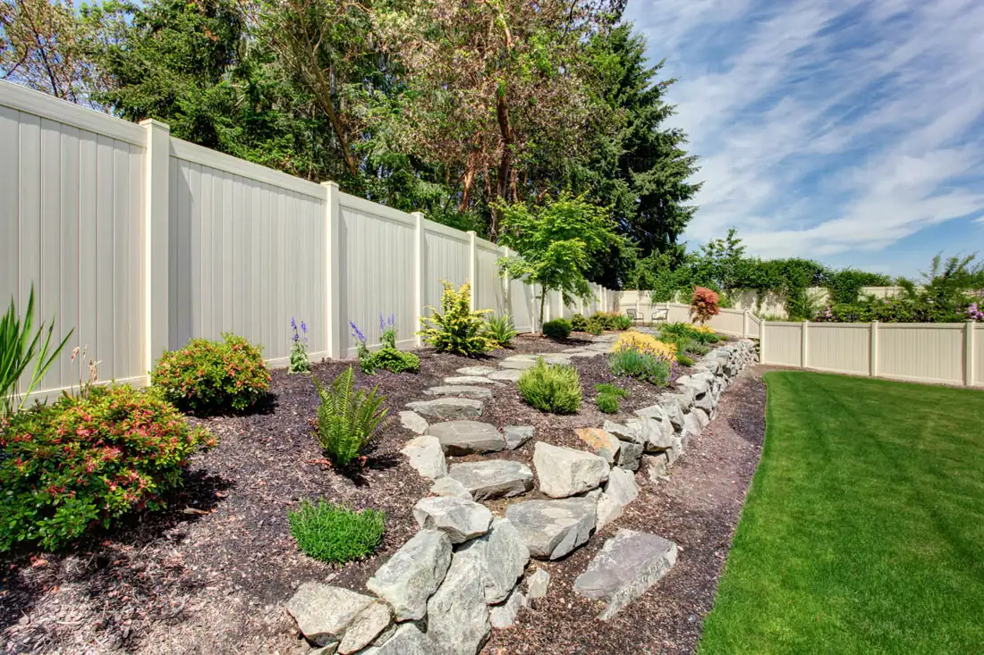 White vinyl privacy fence behind a flowering garden bed